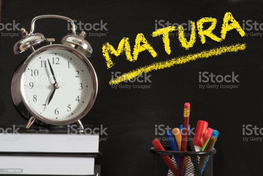 An alarm clock, textbooks and blackboard with the word Abitur in Poland